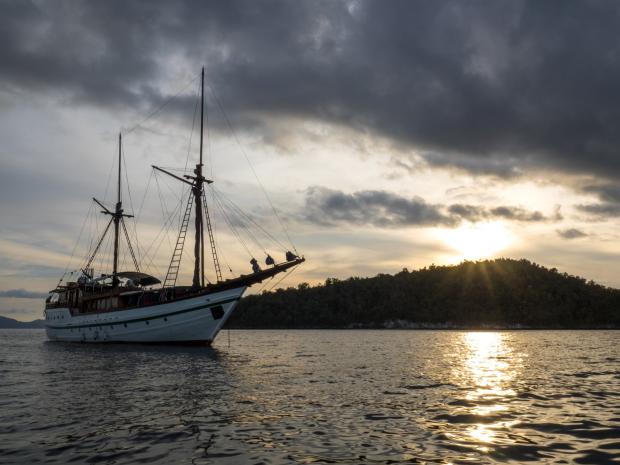 Ship sailing out on ocean with island in the background.