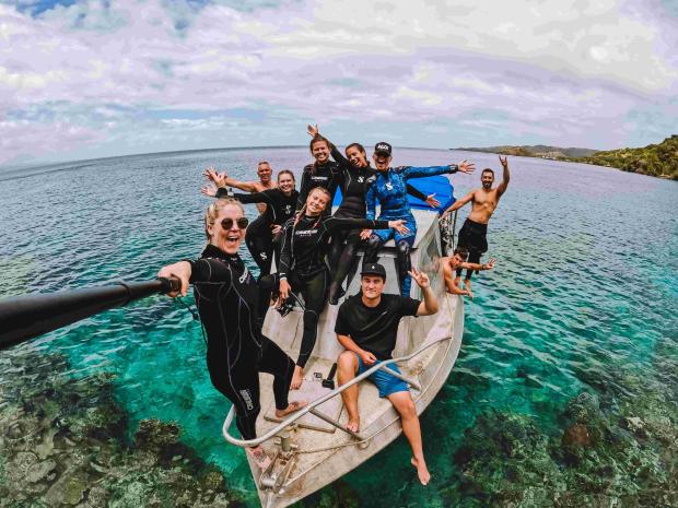 Group of scuba divers taking a photo together on a boat