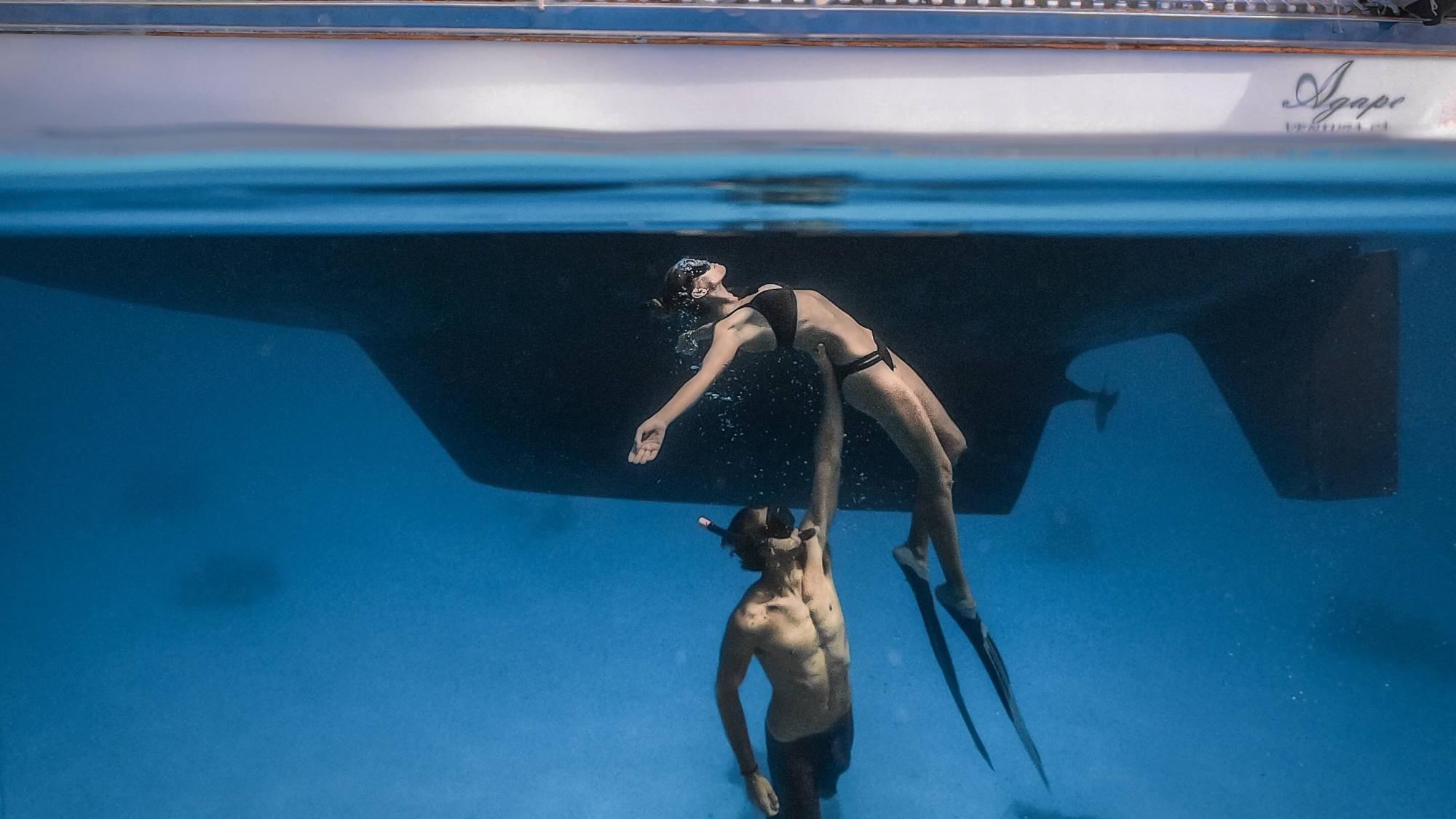 Rachel Moore and Josh Shankle known as Voyages of Agape with an incredible pose underwater near their boat